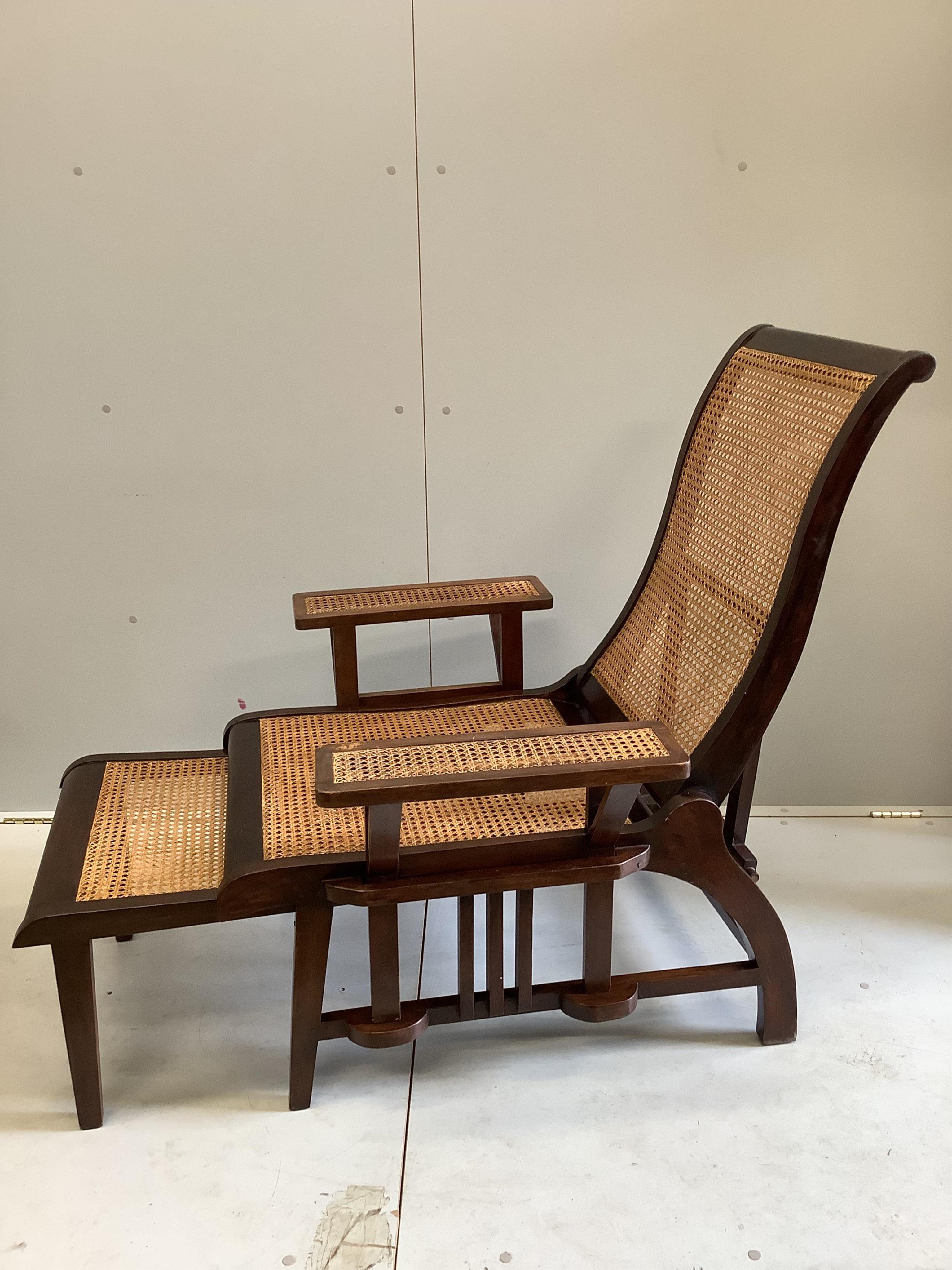 A pair of mid 20th century caned hardwood reclining garden chairs with integral sliding footrests and detachable armrests, width 85cm, depth 90cm, height 106cm. Condition - good